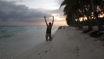photo de Jenna assise sur une plage  de dos au coucher du soleil