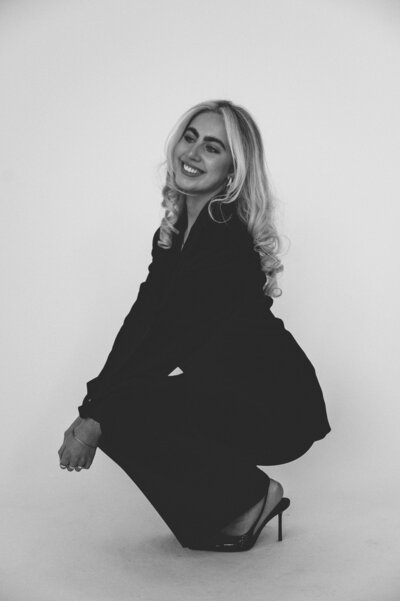 Editorial black and white photo of Amelia Waters crouching in heels, showcasing the founder of Sunday Social Collective