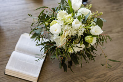 Open Bible on a table next to a floral arrangement