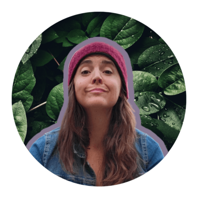 Woman in denim shirt smiling with leaves in the background