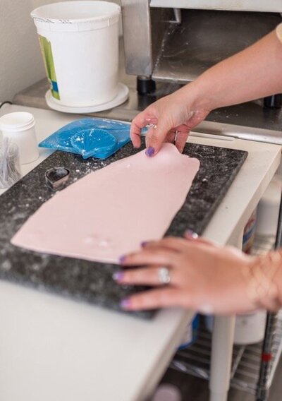 rolling out gumpaste paper thin with a sheeter to make sugar flower petals