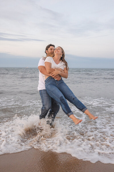 Idaho Wedding Photographer Couple twirls in ocean by the cape henry lighthouse