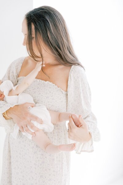 A woman in a white dress holding a baby in her arms.