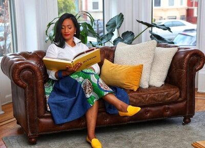 Kizzie Duah reading a book in a stylish outfit