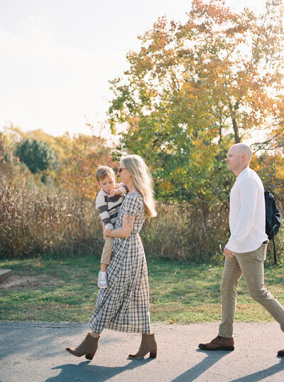 Young family walking casually back their car after a fall photo session captured on film by Little Rock photographer Bailey Feeler