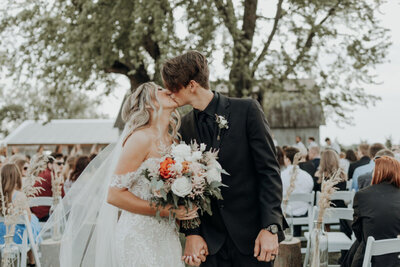 Bride and groom kiss after walking down the aisle
