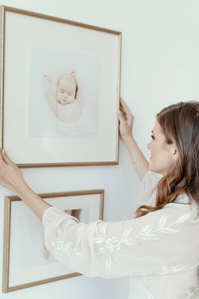 Die Babyfotografin aus Bielefeld hängt ein gerahmtes Babyfoto aus das bei einem Neugeborenenfotoshooting in Paderborn entstanden ist.