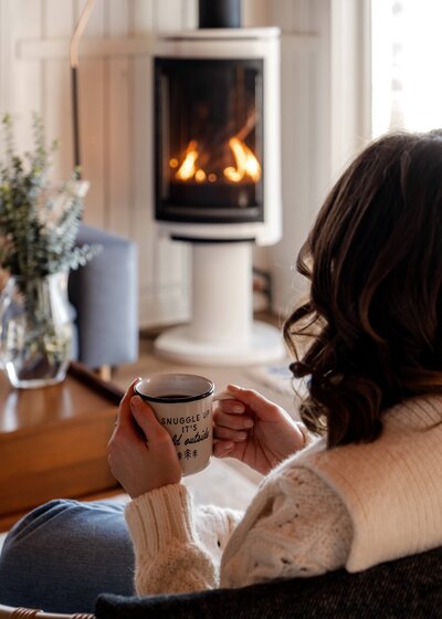 Man drinking from glass in front of fireplace