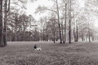 Couple lying in an open field surrounded by trees during a relaxed black-and-white couples session in Alabama — EC Photography
