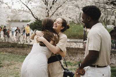 A photographer hugging someone while their partner stands next to them 