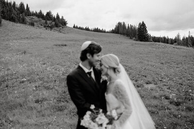 couple in suit and wedding dress lean in towards each other in front of vail colorado mountain