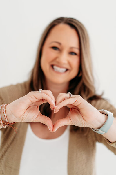 Kim smiling as she makes a heart with her hands