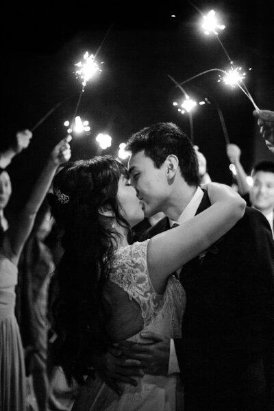 Bride and groom share a kiss as they have their sparkler exit at their wedding