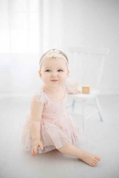 Baby in ruffled romper and crocheted hat sitting in moses basket for photos in a portrait studio in stamford CT