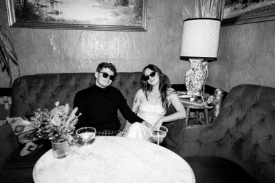 couple sitting down at speakeasy bar in Denver with sunglasses on