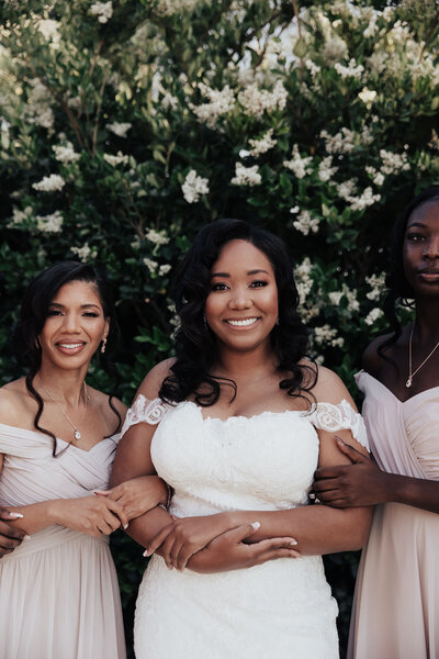 Bride and bridesmaids posing fo r photo holding on to each other