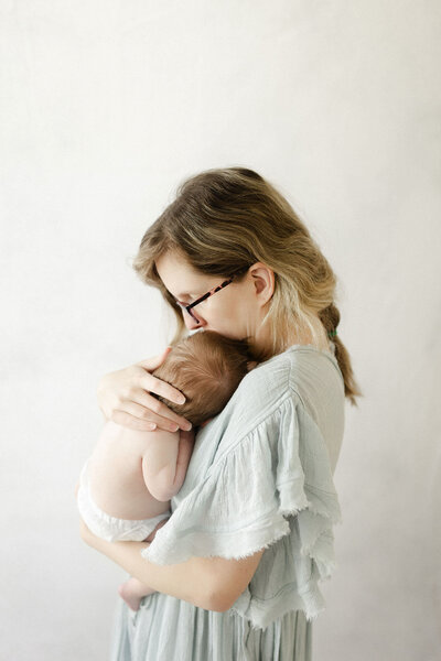 A mom holding her newborn baby during their in-home newborn photography session.