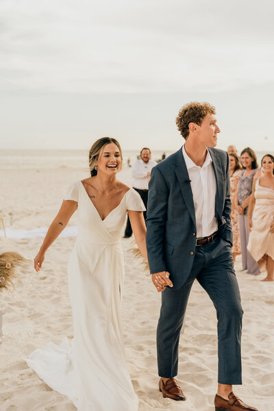 bride and groom walk on beach