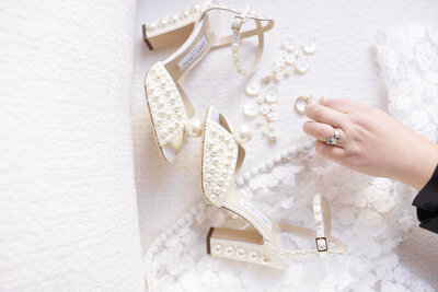 Photographer Michelle Jackson adjusting the beautiful bridal details for a NYC wedding with Jimmy Choo shoes