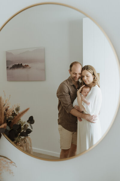 A tender moment between two new Brisbane and their newborn parents caught in the reflection of their entry mirror