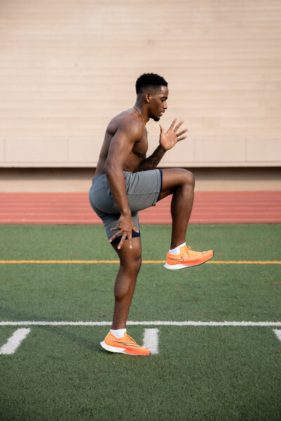 An athletic man stretching on a track, showcasing strength and movement in a fitness-focused branding session.