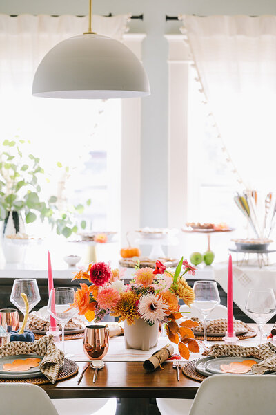 Fall-inspired table setting with red, white, and yellow flower bouquet