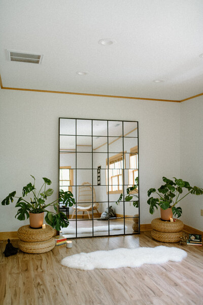 Alyn Wellness Studio space set up with plants, candles, and a big mirror on the wall