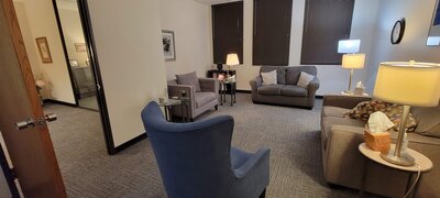 Therapist office with grey carpet and grey and tan couches