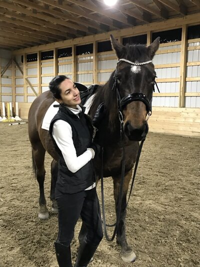Woman and Horse in dressage outfit standing in indoor arena. 