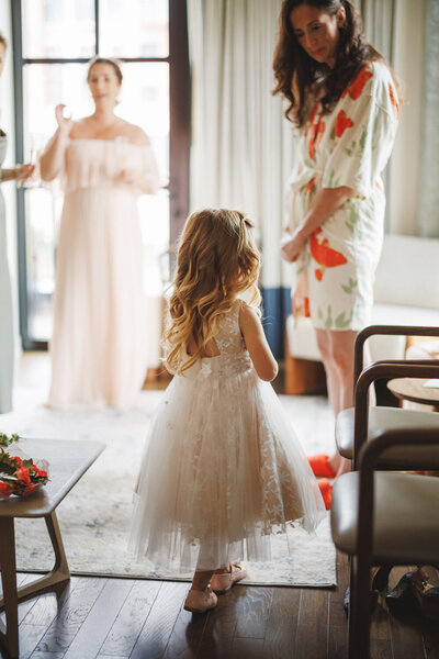 Flower girl in white dress getting ready before ceremony