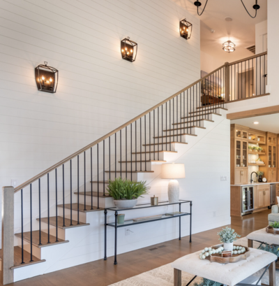 Beautiful Staircase that has white shiplap and sconces and is the style of modern farmhouse.