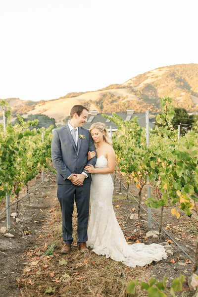 Bride and groom hug while standing in Napa vineyard