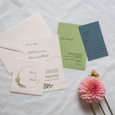 Green blue and nude coloured wedding invitation suite with greenery foliage design and rose gold octagon shape.