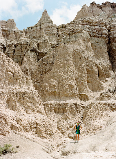 Susannah Storch in a sparkly dress standing among dramatic rock formations in the Badlands.