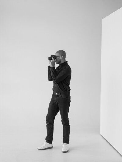 black and white photo in a black turtle neck sitting on the ground smiling of Colorado Wedding Photographer JKG Photography