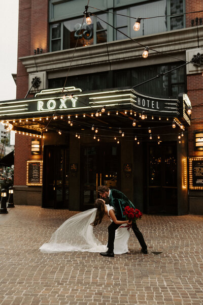 man dipping bride in front of theatre