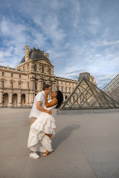 Couple embraces in front of the Louvre in Paris