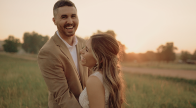 videographer and wedding couple in grass field during sunset
