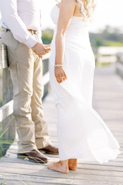 close up of a woman in a white dress holding hands with a man in a white dress shirt and khaki pants
