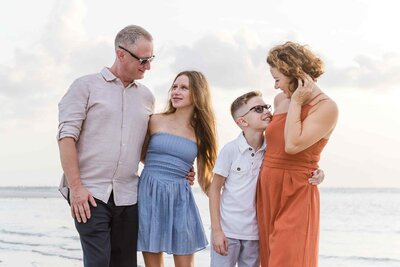 Family of four smiling at each other at the beach