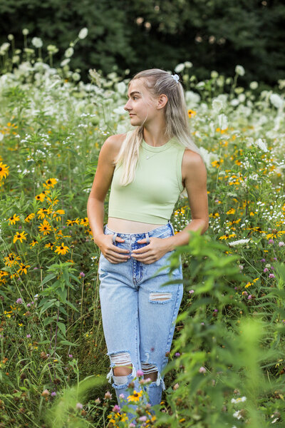 Photo of girl standing in field of flowers looking to the side | Senior Session