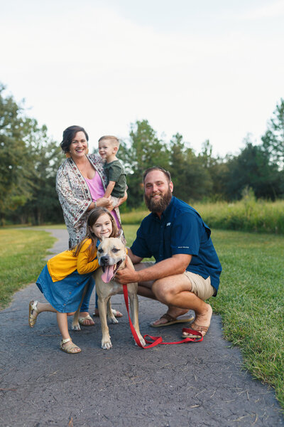 Sweet family of 4 smiling and laughing with dog