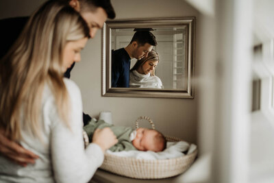 Mom and dad holding their newborn together  in their home in Vancouver