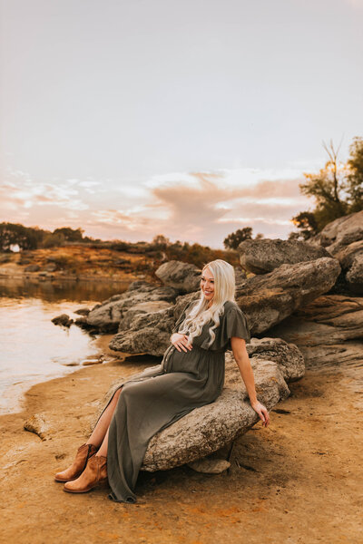 pregnant blond mother sitting on a rock at Grapevine Lake