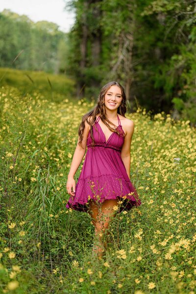 Cuthbertson senior twirls in the tall grass filled with yellow flowers