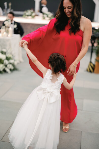 Woman in red dress dancing with flower girl in white dress