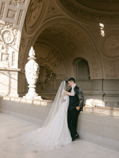 Napa wedding photographer sitting on a stool in a studio, holding a camera with a confident and welcoming expression, ready to capture timeless love stories.