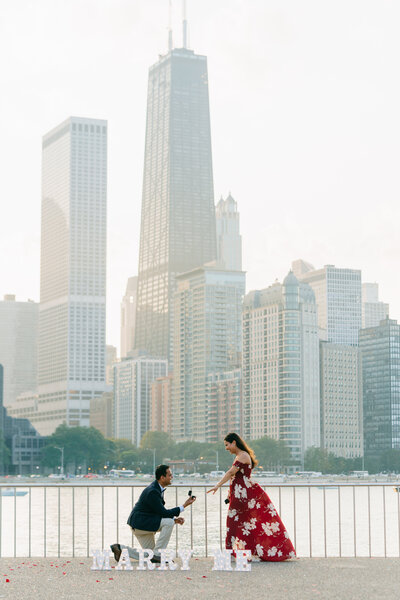 Man proposing to his girlfriend at Milton Lee Olive Park, with Lake Michigan and the John Hancock building in the background