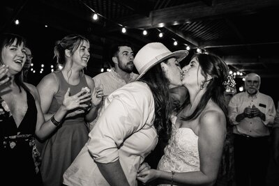 Two brides kiss on the dance floor of their wedding