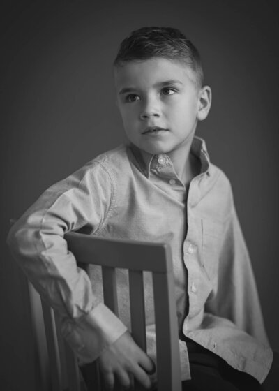 young boy being serious wearing a  dress shirt in a black and white children's portrait captured by Allison Amores Photography